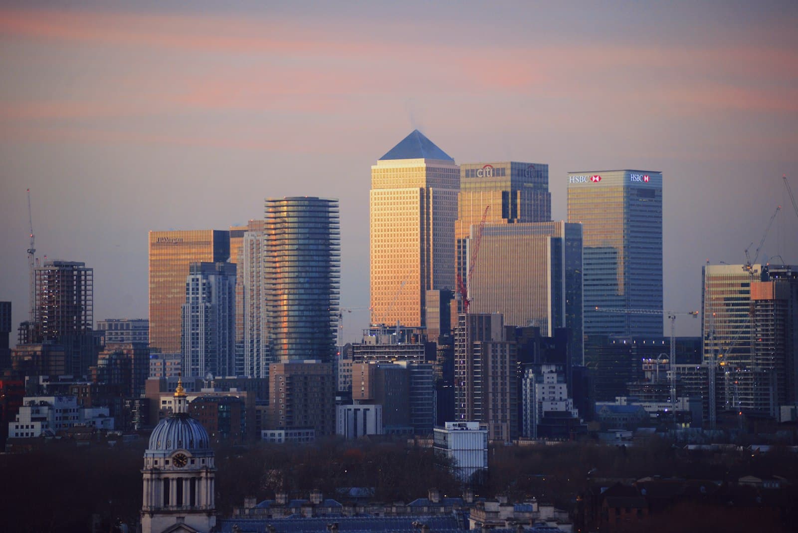 The Canary Wharf skyline at dusk with bank towers lit by the setting sun